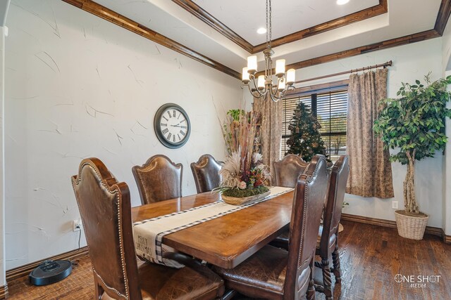 dining area with crown molding, a raised ceiling, dark wood-type flooring, and a chandelier