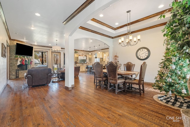 dining space with ornamental molding, a large fireplace, and dark wood-type flooring