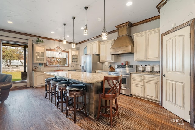 kitchen with hanging light fixtures, stainless steel appliances, cream cabinets, a kitchen island, and custom exhaust hood