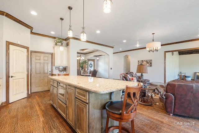 kitchen featuring pendant lighting, a center island, dark wood-type flooring, crown molding, and a breakfast bar area