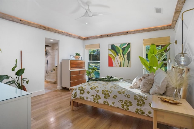 bedroom featuring ensuite bath, visible vents, and wood finished floors