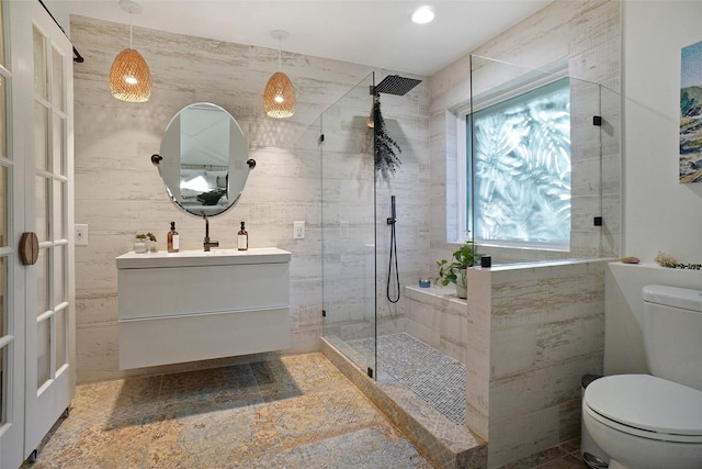 full bathroom with visible vents, toilet, a tile shower, vanity, and tile walls