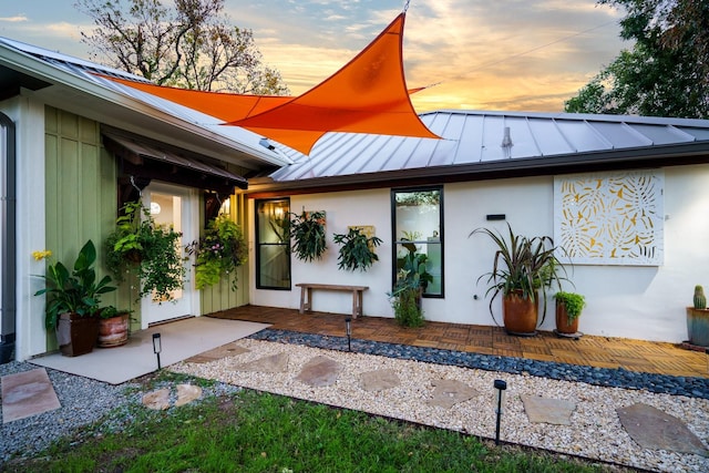 exterior space featuring a standing seam roof, a patio area, metal roof, and stucco siding