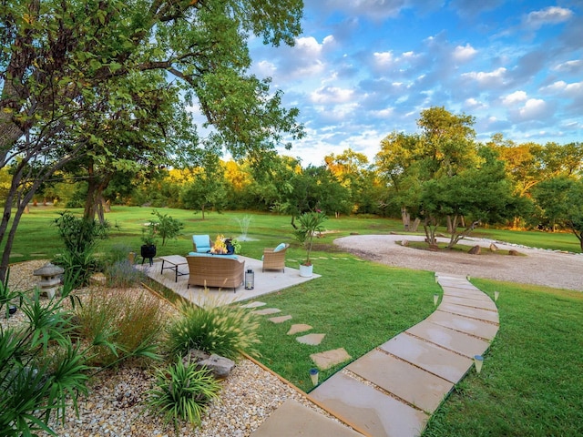 view of property's community featuring a lawn and a patio