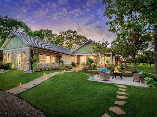 back of house at dusk featuring a standing seam roof, a patio area, a lawn, and an outdoor hangout area