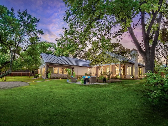 back of house featuring a standing seam roof, an outdoor hangout area, metal roof, and a lawn