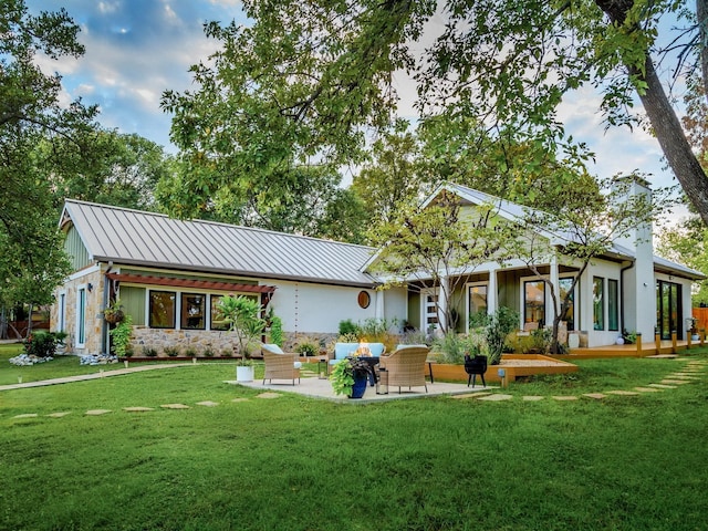 rear view of house with a lawn, a chimney, metal roof, a standing seam roof, and a patio area