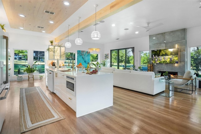 kitchen featuring a fireplace, visible vents, a sink, light wood-type flooring, and oven