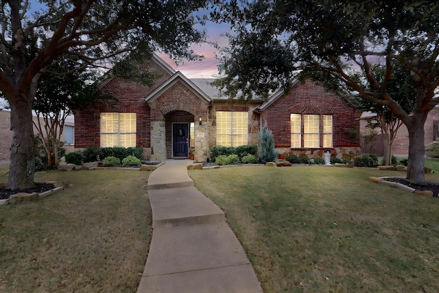 view of front of house with a yard, stone siding, and brick siding