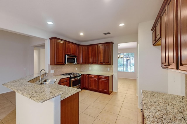 kitchen with sink, stainless steel appliances, light stone countertops, decorative backsplash, and kitchen peninsula