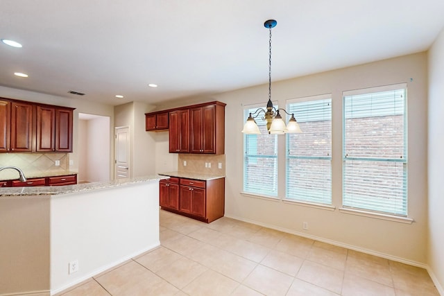 kitchen with light stone counters, hanging light fixtures, plenty of natural light, and sink