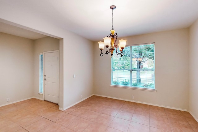 tiled spare room with a notable chandelier