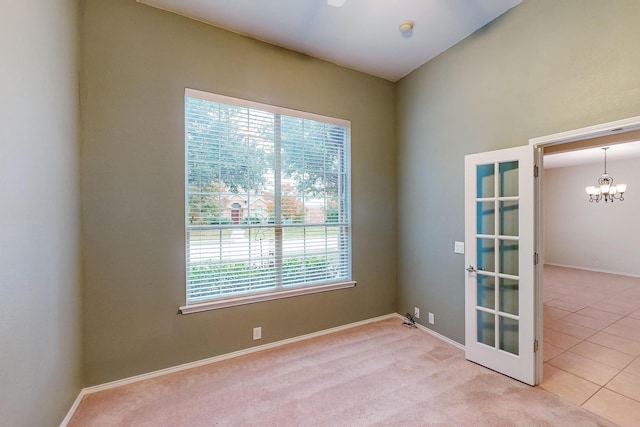 unfurnished room with light colored carpet, french doors, and a chandelier