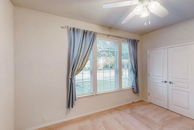 unfurnished bedroom with light carpet, a closet, and ceiling fan