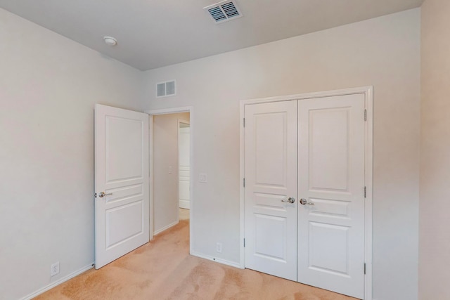 unfurnished bedroom featuring light carpet and a closet