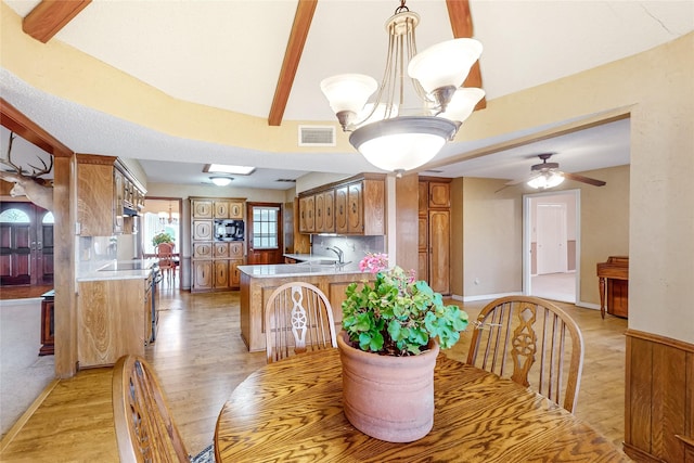 dining room with beam ceiling, ceiling fan with notable chandelier, and light hardwood / wood-style flooring