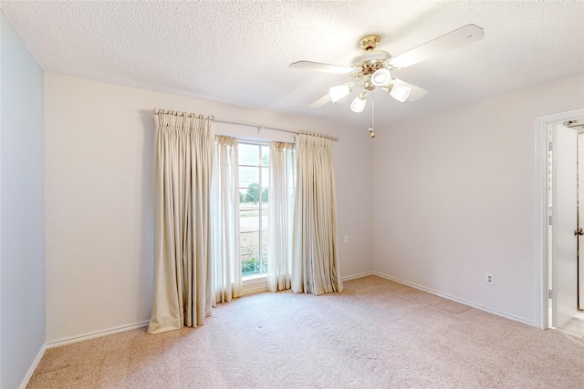 empty room featuring ceiling fan, a textured ceiling, carpet, and baseboards