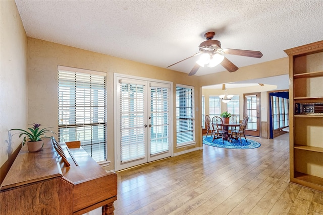 interior space featuring light wood-style floors, ceiling fan, a textured ceiling, and french doors