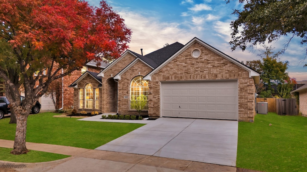 view of front of property featuring a garage, a yard, and central AC