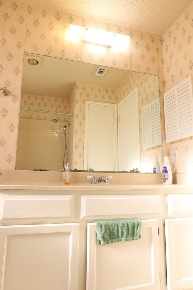 bathroom with vanity, a textured ceiling, and walk in shower