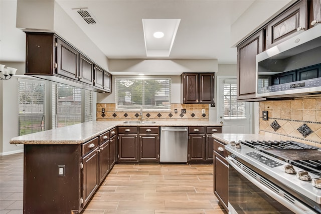 kitchen featuring appliances with stainless steel finishes, backsplash, dark brown cabinets, and sink