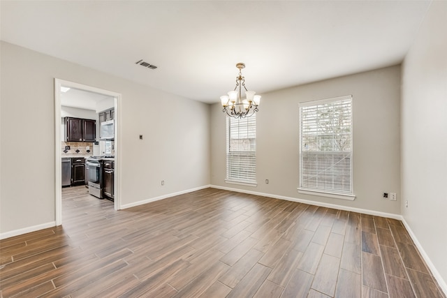 spare room featuring hardwood / wood-style floors and a notable chandelier