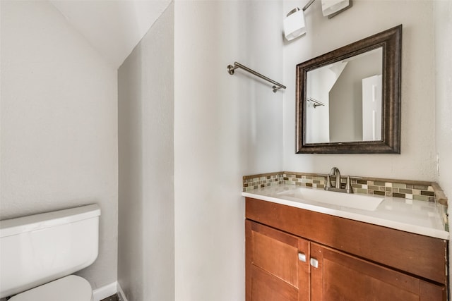 bathroom with decorative backsplash, vanity, vaulted ceiling, and toilet