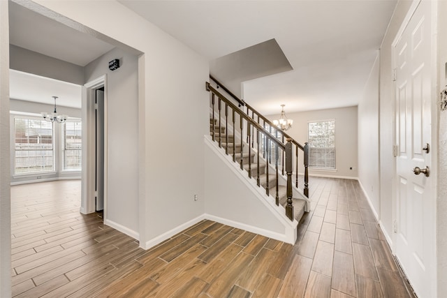 entryway with a healthy amount of sunlight, dark wood-type flooring, and an inviting chandelier