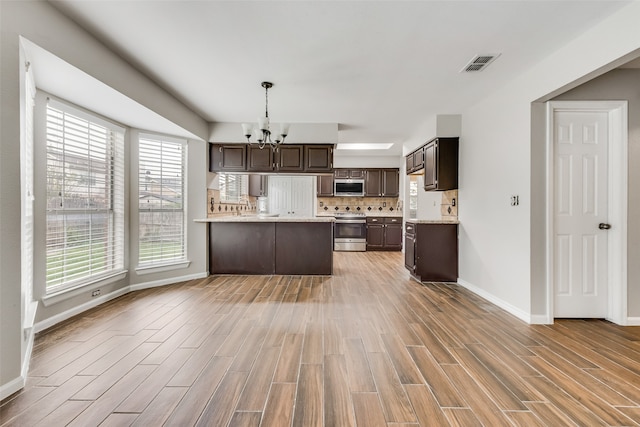 kitchen featuring dark brown cabinets, light hardwood / wood-style floors, decorative light fixtures, and appliances with stainless steel finishes