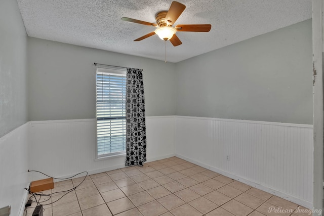 unfurnished room with ceiling fan, a textured ceiling, and light tile patterned floors