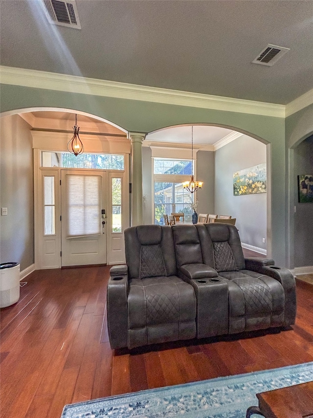 living room with ornate columns, a textured ceiling, crown molding, dark wood-type flooring, and a chandelier