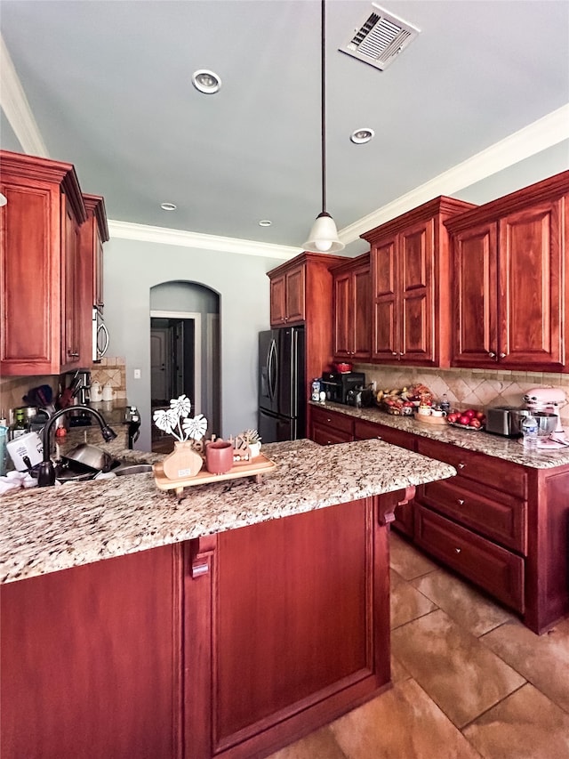 kitchen with kitchen peninsula, tasteful backsplash, black fridge, ornamental molding, and pendant lighting