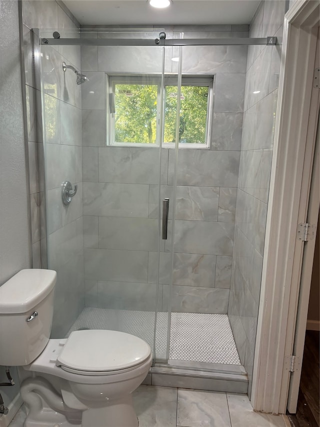 bathroom with a shower with door and toilet