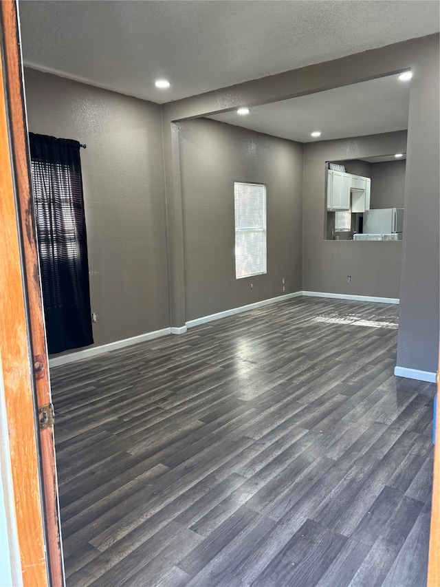 empty room with a textured ceiling and dark wood-type flooring