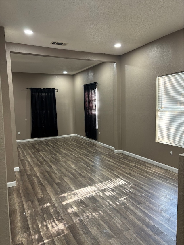 spare room featuring a textured ceiling and dark hardwood / wood-style flooring