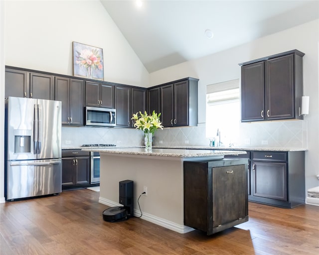 kitchen featuring light stone countertops, a center island, dark hardwood / wood-style floors, and appliances with stainless steel finishes