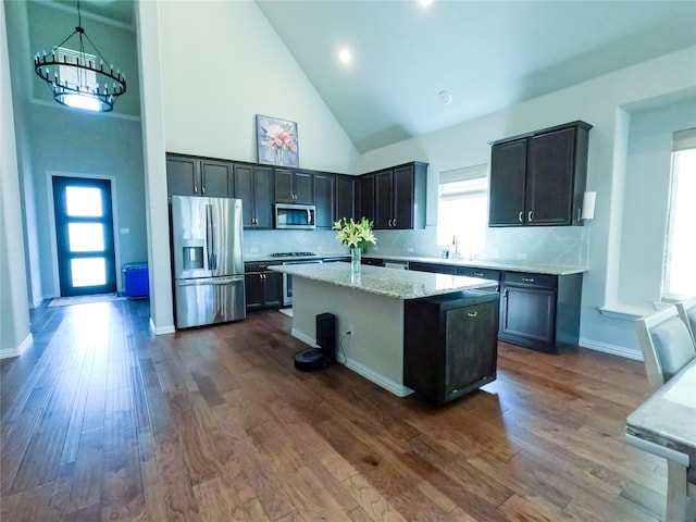 kitchen with dark hardwood / wood-style flooring, stainless steel appliances, high vaulted ceiling, a center island, and hanging light fixtures