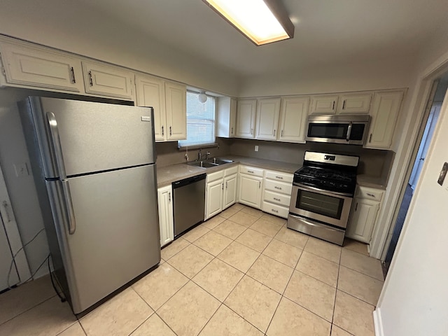 kitchen with white cabinetry, sink, light tile patterned floors, and stainless steel appliances