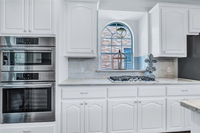 kitchen featuring decorative backsplash, white cabinets, and appliances with stainless steel finishes