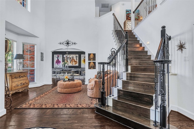 stairway featuring a chandelier, a towering ceiling, and wood-type flooring