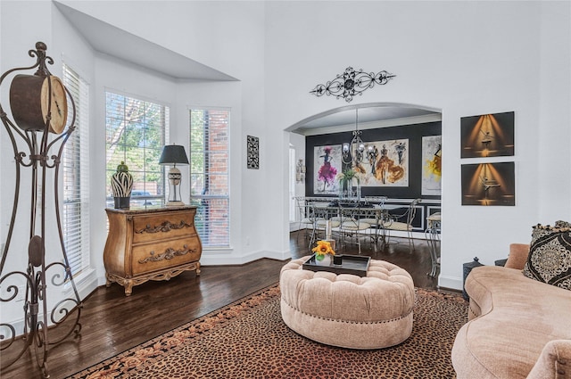 sitting room featuring a towering ceiling, dark hardwood / wood-style floors, an inviting chandelier, and ornamental molding