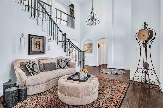 living room featuring a chandelier, a towering ceiling, and dark wood-type flooring