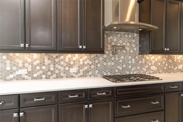 kitchen with wall chimney exhaust hood, dark brown cabinets, and backsplash