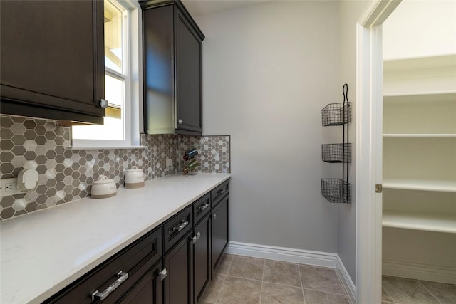 kitchen featuring dark brown cabinets, backsplash, and light tile patterned floors