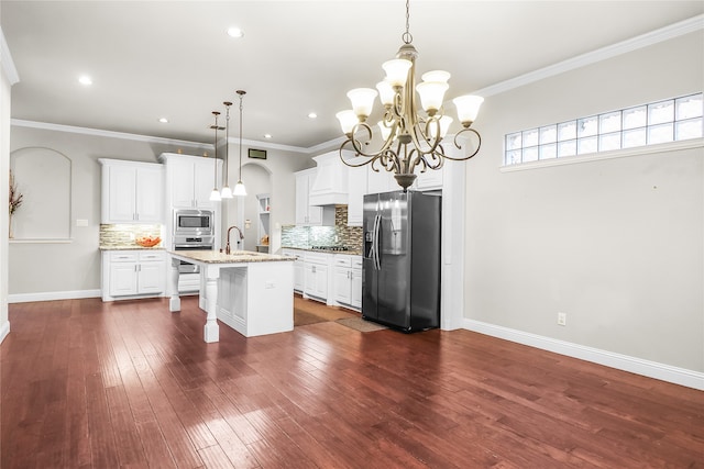 kitchen with pendant lighting, a kitchen island with sink, dark hardwood / wood-style floors, appliances with stainless steel finishes, and white cabinetry