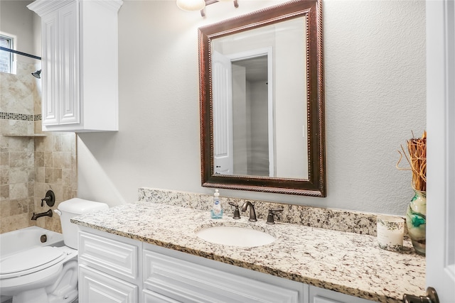 full bathroom with tiled shower / bath, vanity, and toilet