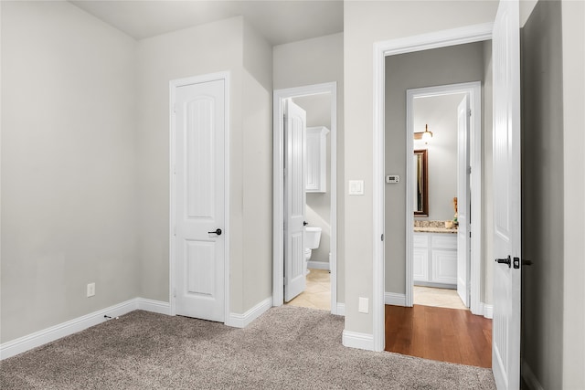 unfurnished bedroom featuring light colored carpet and connected bathroom