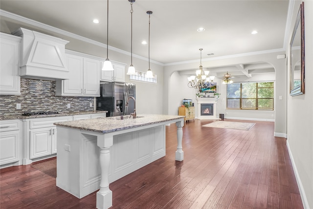 kitchen featuring a kitchen bar, a kitchen island with sink, white cabinets, and dark wood-type flooring