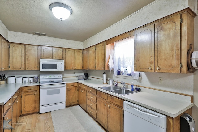 kitchen featuring white appliances, ornamental molding, sink, and a textured ceiling