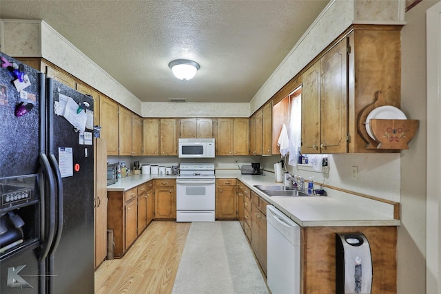 kitchen featuring white appliances, sink, a textured ceiling, and light wood-type flooring